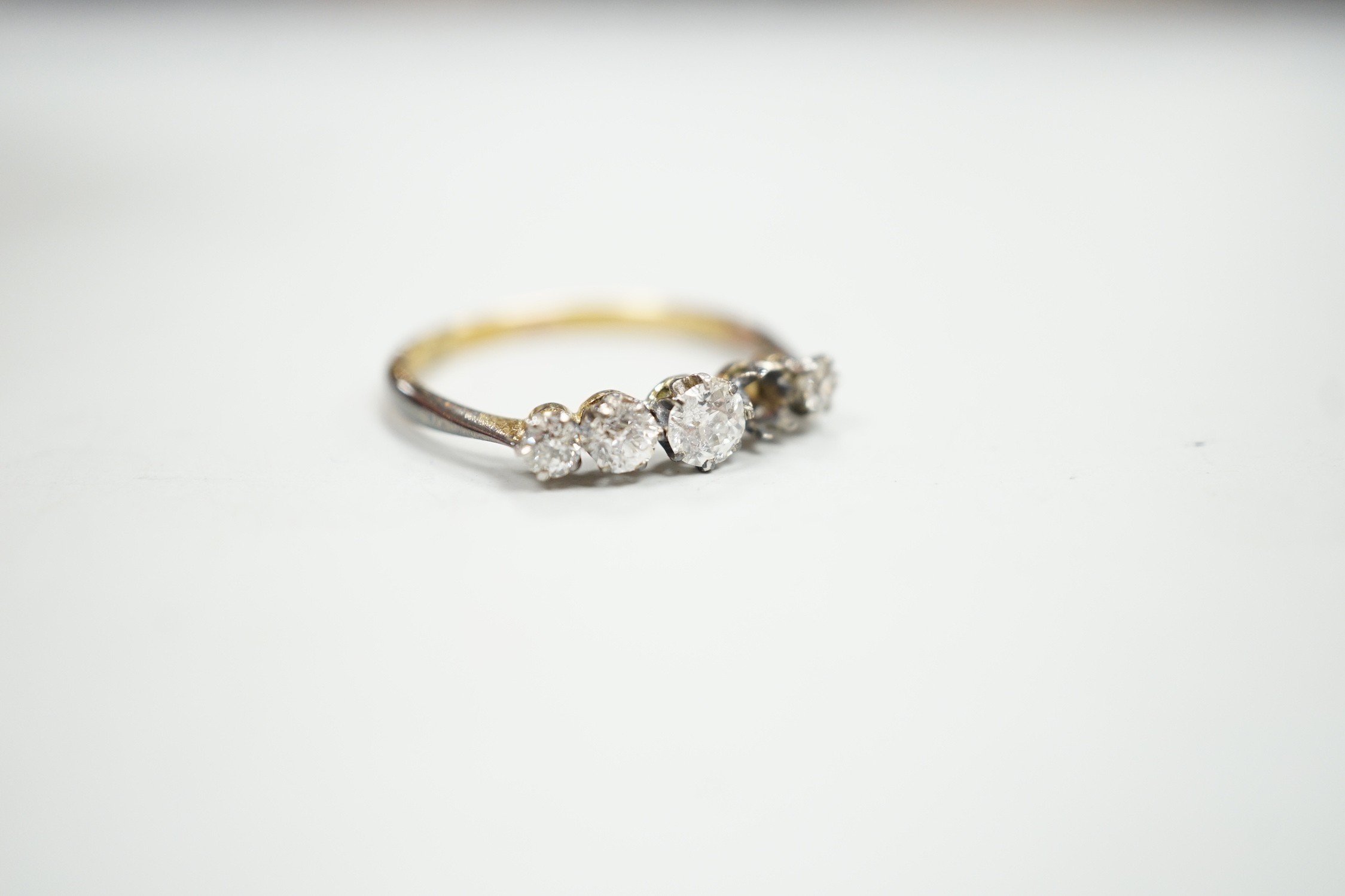 An 18ct and graduated five stone diamond set half hoop ring, size P, gross weight 1.9 grams, one stone loose but present.